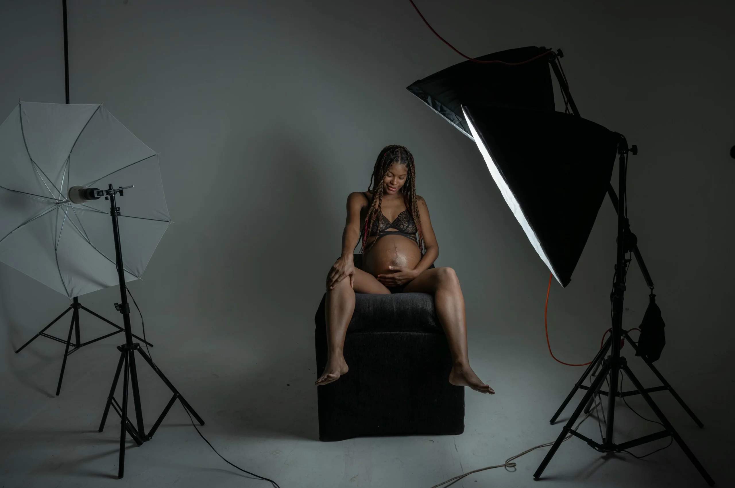 Pareja posando en un estudio fotográfico en RD, con la mujer embarazada y su baby bump resaltado por iluminación profesional.